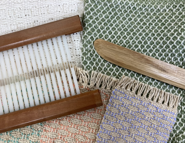Image of a rigid heddle and pick-up stick resting on fabric samples.